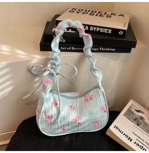 Detail of light blue floral handbag with scrunchie strap and pink bow prints