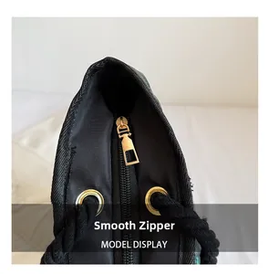 Détail de la fermeture éclair dorée et de la poignée en corde sur un sac noir