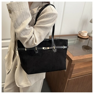 Détail du sac cabas en daim noir avec boucle dorée et bandoulière sur l'épaule