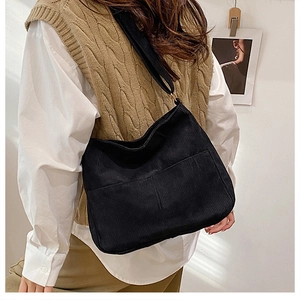 Detail of black corduroy tote bag featuring two front pockets and wide shoulder strap