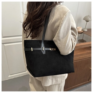 Vue détaillée du grand sac cabas en daim noir avec boucle dorée porté à l'épaule