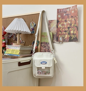 Détail du sac bandoulière en toile avec poche PVC transparente et badges décoratifs