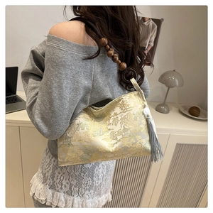 Detail of embroidered silk handbag featuring wooden bead handle and silk tassel detail