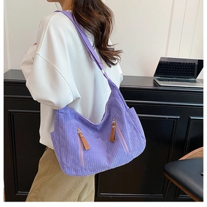 Detail of purple corduroy crossbody bag with dual zip pockets and wide shoulder strap