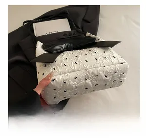 Close-up of white embossed tote bag featuring black bow patterns and large leather bow detail