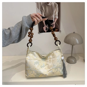 Detail of embroidered beige floral pattern and wooden bead handle on a handbag