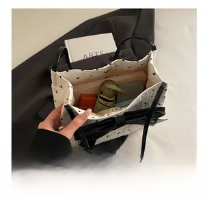 Spacious interior of white polka dot tote bag holding a phone, umbrella, and notebook