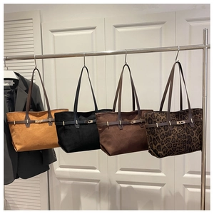 Vue détaillée de quatre sacs cabas en daim de différentes couleurs sur un support de présentation
