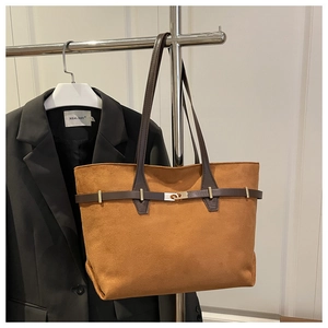 Détail d'un sac cabas en daim marron avec bandoulières en cuir foncé et boucle métallique