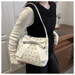 Detail of white quilted tote bag featuring a large bow and black bunny embroidery motifs