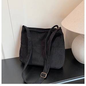 Detail view of black corduroy tote bag featuring golden metal adjustment buckle