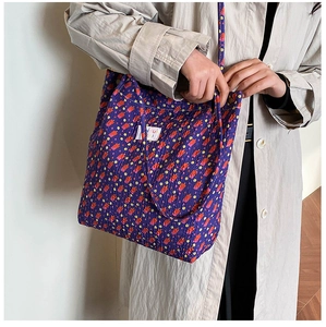 Détail du sac cabas en toile fleurie violette avec texture matelassée et étiquette