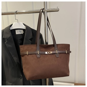 Détail du sac cabas en daim marron foncé avec lanières en cuir et boucle en métal doré