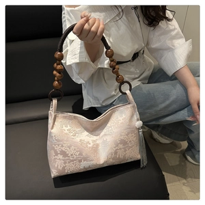 Close-up of silk embroidery handbag featuring traditional landscape art and wooden bead handle