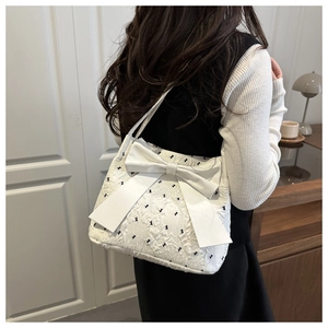 Detail of white seersucker tote bag featuring a large bow and black polka dot patterns