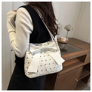 Detail shot of white seersucker tote bag featuring large bow and black bow embroidery