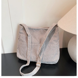Detail view of light grey corduroy tote bag with golden metal strap adjuster and pocket