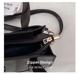 Detail of dark brown oil wax leather bag featuring a gold metal zipper and logo