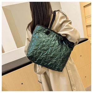 Détail du sac cabas vert matelassé en étoile avec des anses en corde sur un manteau