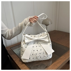 Detail of white seersucker tote bag with large bow and black bow pattern texture