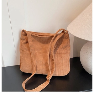 Detail view of the soft brown corduroy tote bag showing vertical ribbed texture and side pocket