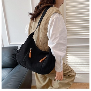 Detail of black corduroy shoulder bag with textured stripes and leather zipper pulls