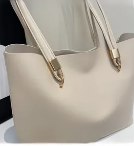 Detail view showing polished gold hardware and soft cream leather of the minimalist tote bag
