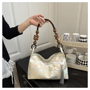 Detail showing embroidered brocade silk bag with wooden bead handle and tassel charm