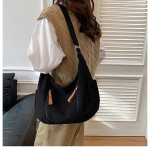 Detail view of black corduroy hobo bag with side pockets and brown leather pulls