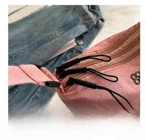 Détail du sac en nylon rose avec triple fermeture éclair et emblème floral chic
