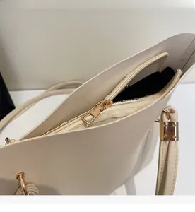 Detailed close-up showing the smooth golden zipper and cream white faux leather bag texture