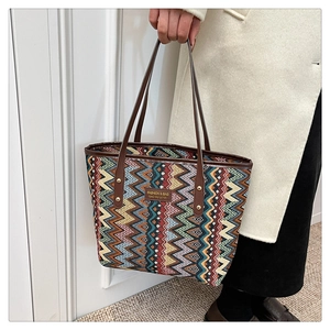 Close-up of geometric wave pattern fabric and brown leather handle on tote bag