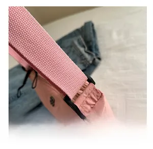 Détail du sac en toile rose montrant l'anneau en plastique noir et la bandoulière tissée