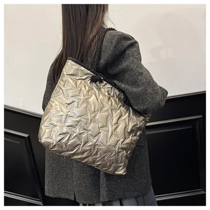 Détail d'un sac cabas doré avec surpiqûres en étoile et poignées en corde noire