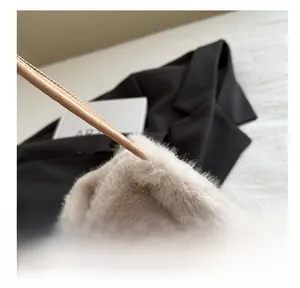 Detailed close-up of fluffy beige faux fur texture with a matching slim leather strap
