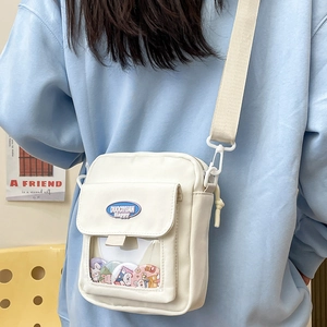 Détail du sac ita blanc avec fenêtre en PVC transparent et plusieurs badges de dessin animé