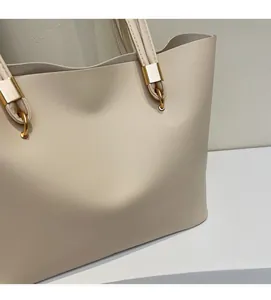 Detail of soft beige leather texture and gold metal buckle on a large tote bag