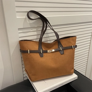 Grand sac cabas en daim marron avec lanières en cuir et fermoir doré sur fond blanc épuré