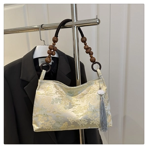 Detailed view of gold brocade handbag with landscape embroidery and beaded handle