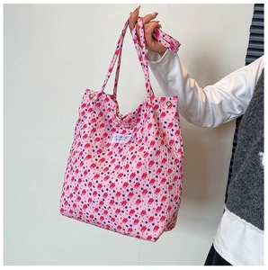 Gros plan sur le sac cabas rose fleuri montrant la texture du tissu et l'étiquette logo