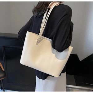 Detail of the cream leather tote bag showing the sleek shoulder strap and large capacity