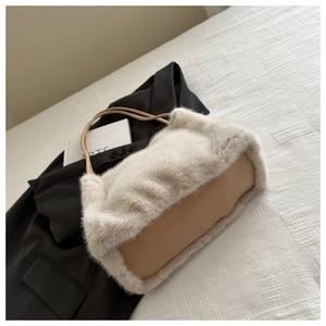 Detail view of plush beige faux fur tote bag with khaki leather straps on a suit jacket