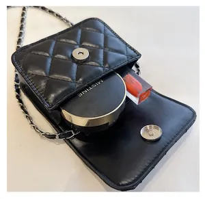Detail view of the black quilted small square bag with its silver magnetic closure and chain