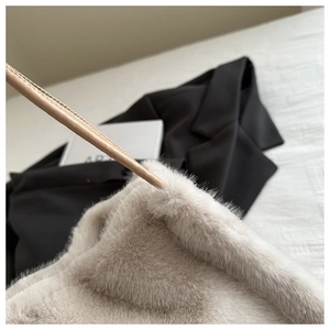 Detail of soft beige faux fur texture and leather strap on a plush tote bag for women