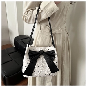 Detail of white quilted tote with black rabbit patterns and a large leather bow