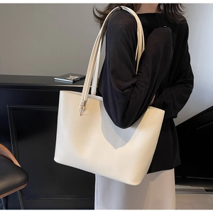 Detailed view of large white tote bag with slim shoulder straps and gold hardware details