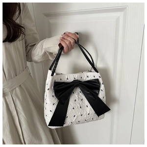 Close-up of seersucker tote bag with black bows on white pleated texture fabric