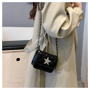 Detail of black quilted mini bag with rhinestone star and silver chain strap