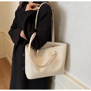 Detailed close-up of cream PU leather tote bag showing slim straps and matte texture