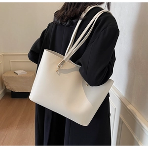 Minimalist beige tote bag shown from the back view on model for size and capacity reference
